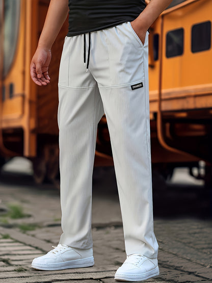 Person wearing white pants with a brand logo, standing on a street with a blurred vehicle in the background.