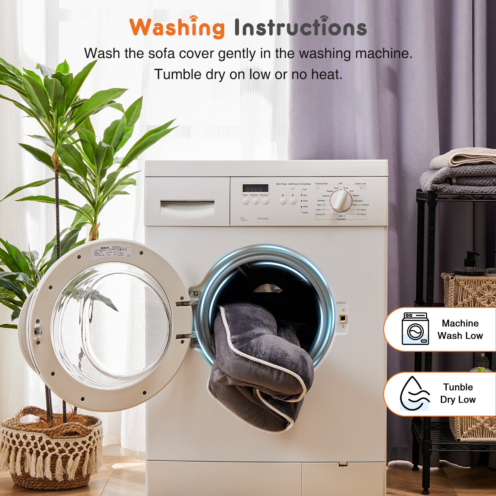 Washing machine with a gray sofa cover inside, surrounded by a plant and a shelf with folded clothes.