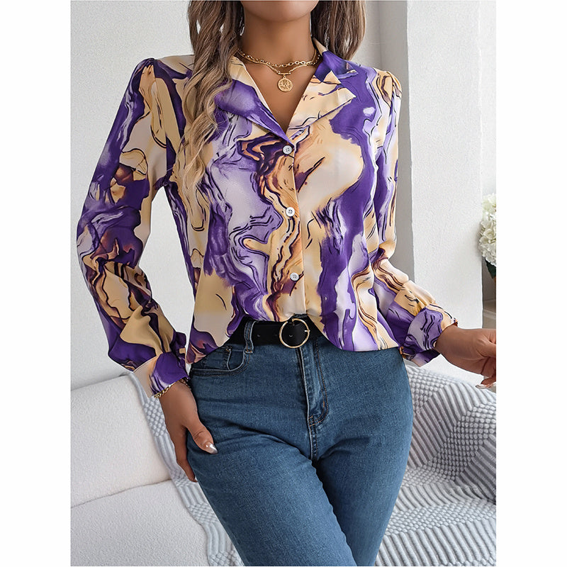 Woman wearing a purple and gold marbled blouse with blue jeans indoors.