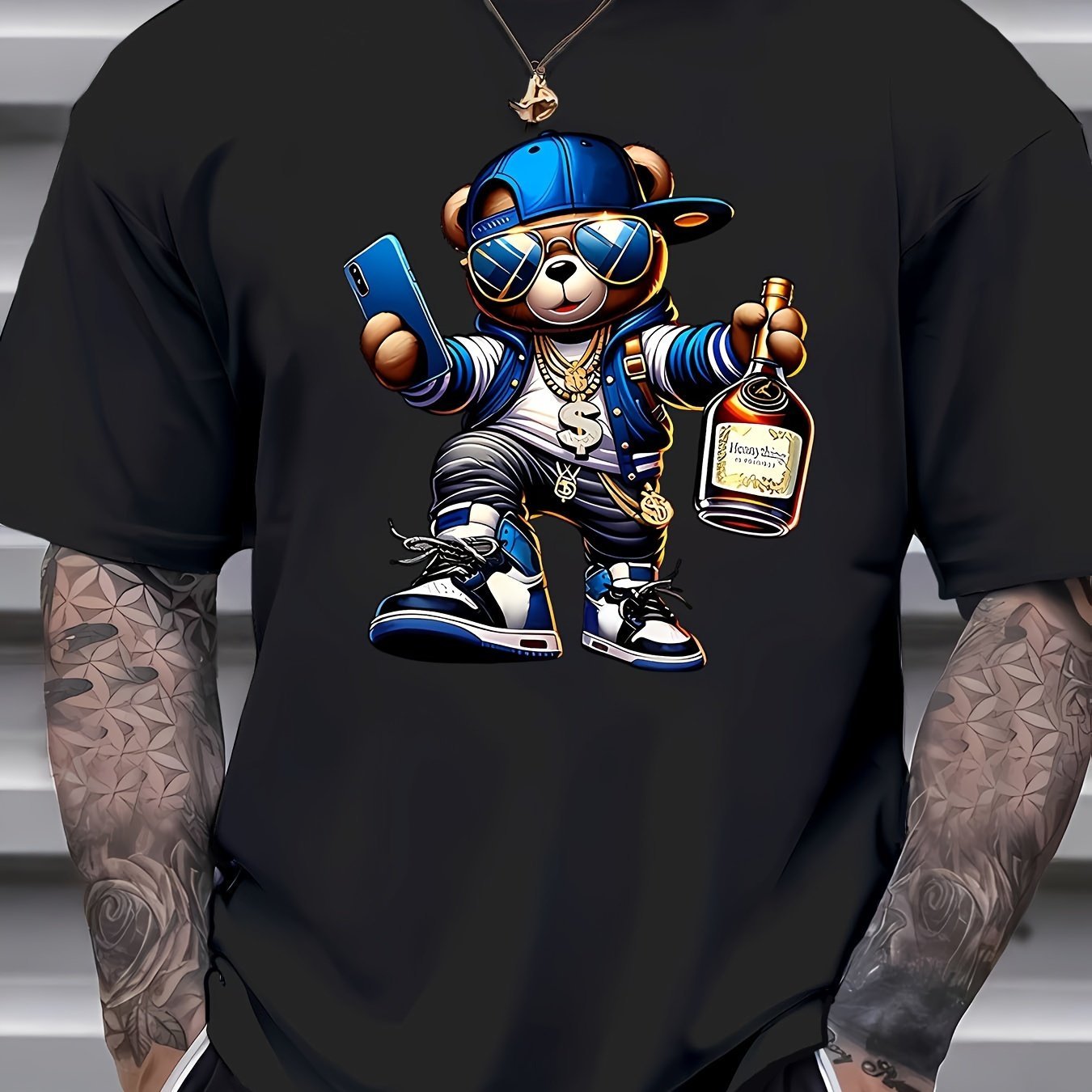 Black t-shirt with a cartoon bear holding a phone and bottle, worn by a person with tattoos.