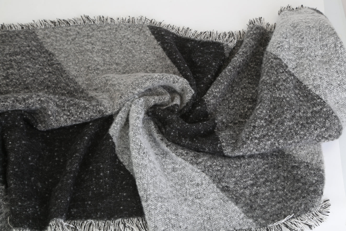 Checkered blanket with fringes in gray and black on a white background