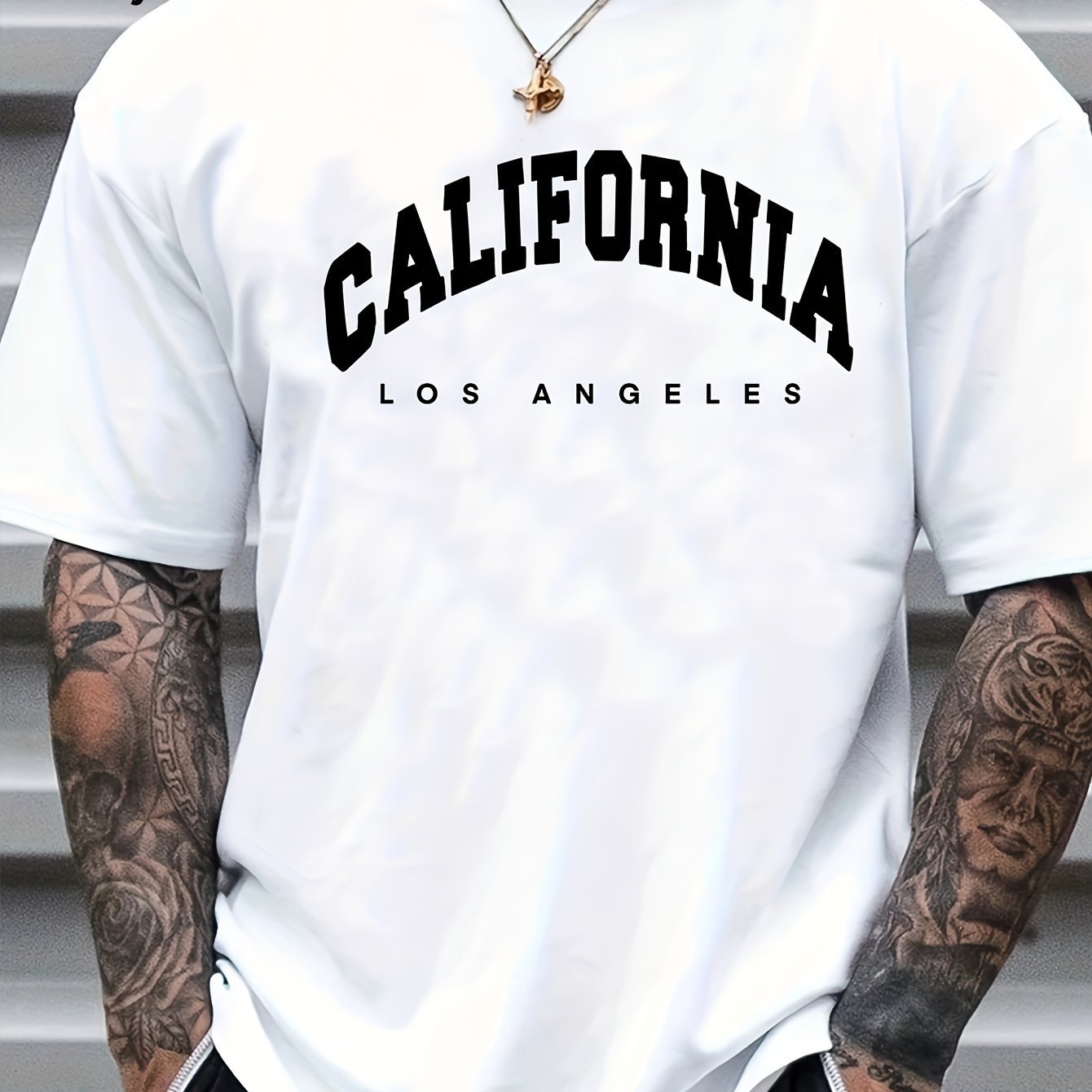 White t-shirt with 'California Los Angeles' text worn by a person with tattoos.