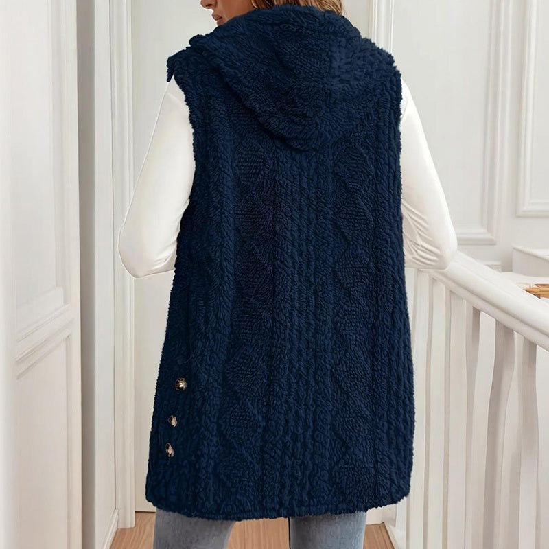 Person wearing a navy blue textured vest with buttons in a neutral setting