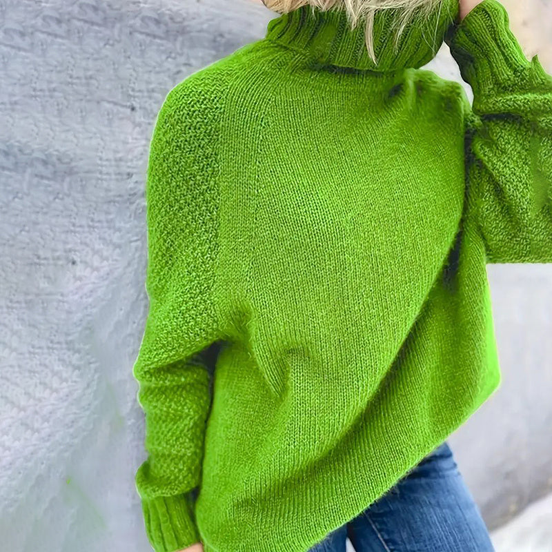 Green knitted sweater worn by a person against a light gray background