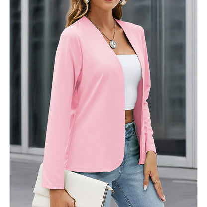 Woman wearing a pink blazer over a white top and blue jeans, standing in an urban setting.