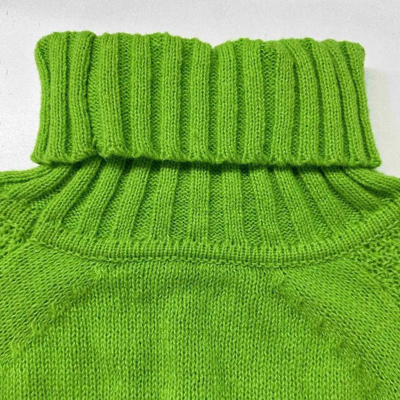 Close-up of a green knitted sweater with a ribbed collar on a light gray background