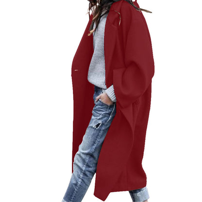 Person wearing a long red coat over a light gray sweater and blue jeans on a white background