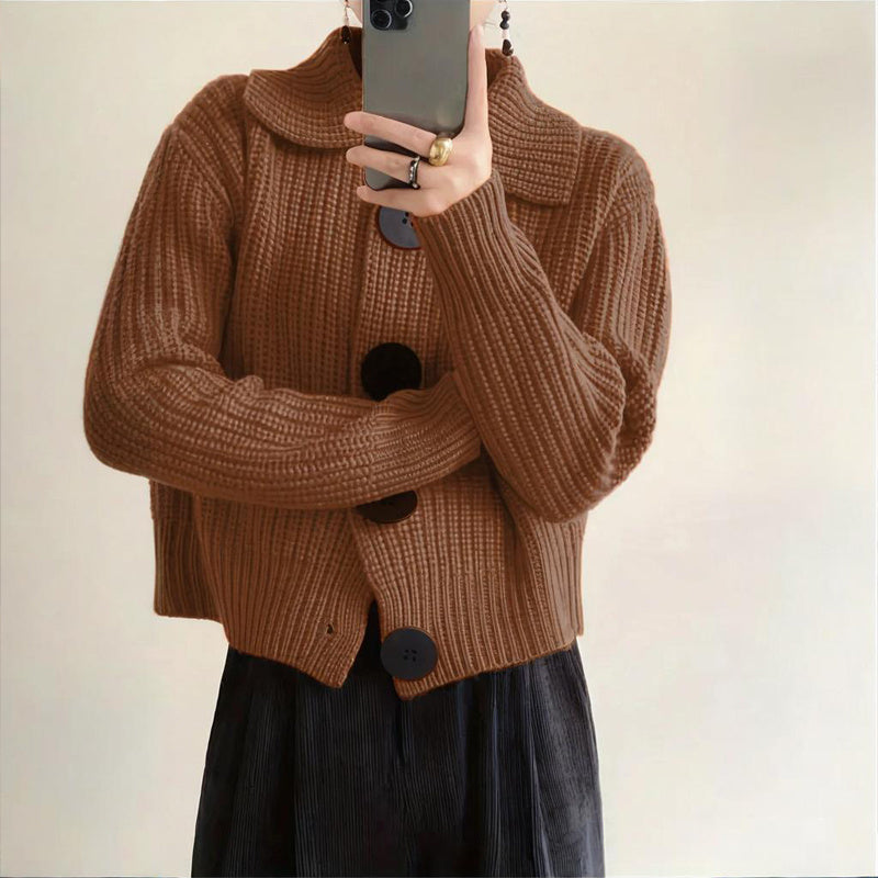 Person wearing a brown knitted cardigan with black buttons against a plain background