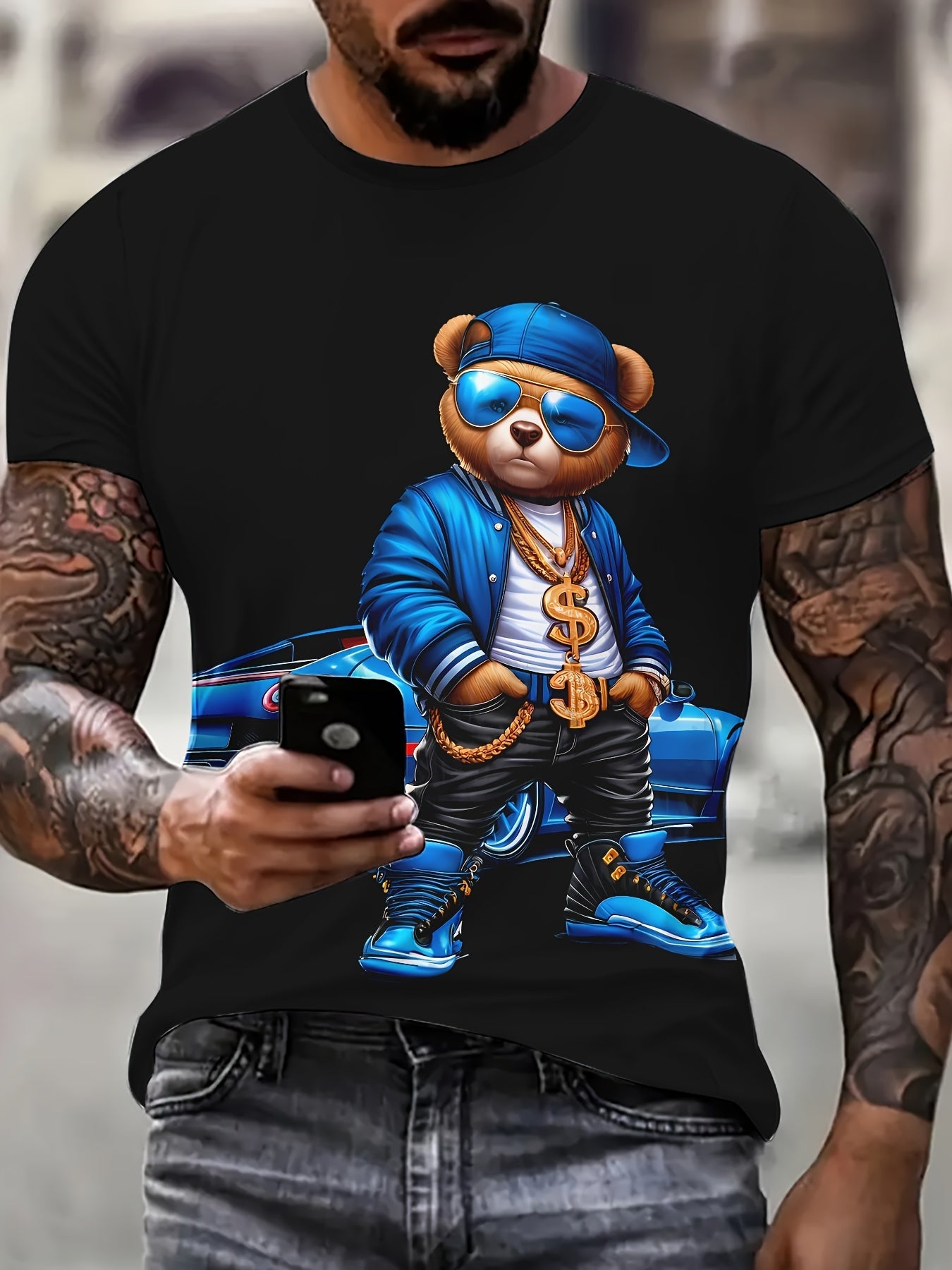 Black t-shirt with a bear graphic wearing sunglasses and a blue jacket, held by a person.