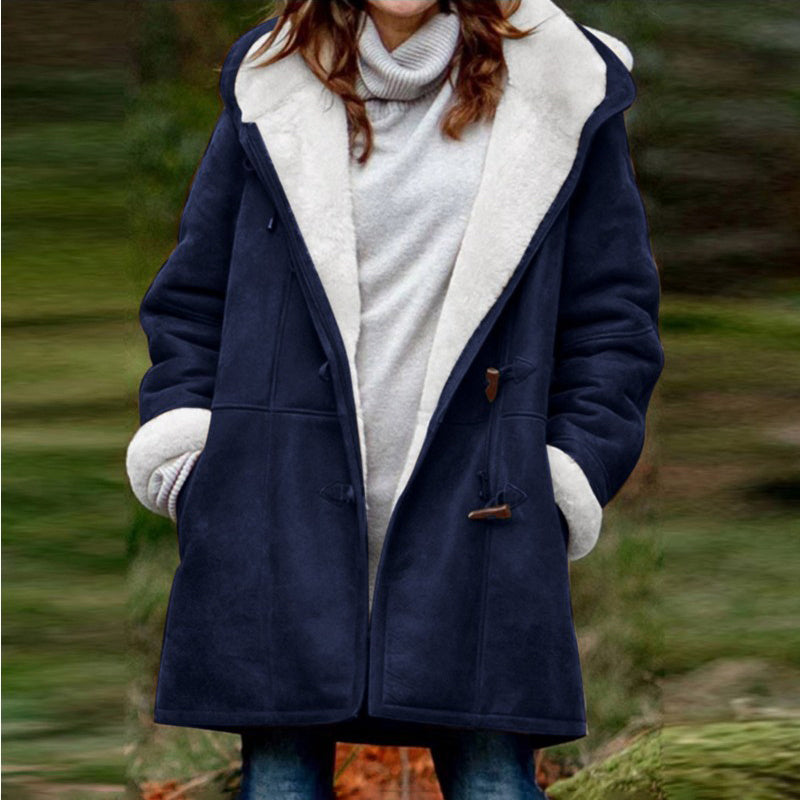 Person wearing a navy blue coat with white fur lining in an outdoor setting